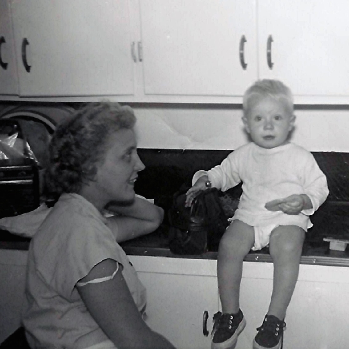 A photo of a young boy cooking with his mom in the 1950s